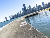 an empty sidewalk that leads to the city of chicago's skyline, which is in the middle of the lake