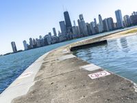 an empty sidewalk that leads to the city of chicago's skyline, which is in the middle of the lake