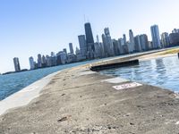 an empty sidewalk that leads to the city of chicago's skyline, which is in the middle of the lake