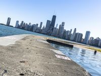 an empty sidewalk that leads to the city of chicago's skyline, which is in the middle of the lake