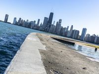 an empty sidewalk that leads to the city of chicago's skyline, which is in the middle of the lake