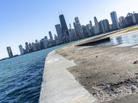 an empty sidewalk that leads to the city of chicago's skyline, which is in the middle of the lake