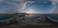 an image of a city as seen through a fish eye lens on water from a concrete pier