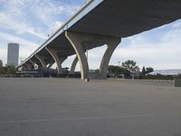 a long bridge above a parking lot full of cars parked under it's bridges