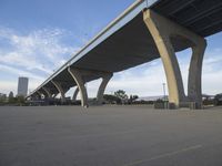 a long bridge above a parking lot full of cars parked under it's bridges