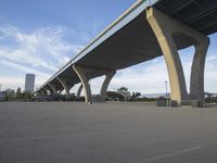 a long bridge above a parking lot full of cars parked under it's bridges