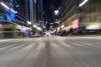 cars driving along an empty city street at night with the city light on and one is blurred