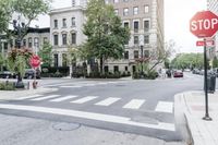 an empty street with cars parked on either side of it, and there's a red stop sign over the road