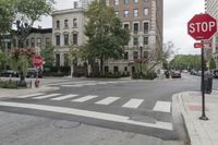 an empty street with cars parked on either side of it, and there's a red stop sign over the road