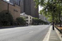 a city street with several tall buildings in the background and many plants lining the road