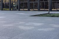 a small child is running in front of the glass buildings on the street as he rides a skateboard