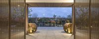 a hallway leads to a garden with gold sculptures in front of an open walkway and a stone path that has trees growing beside