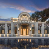 there is a large building with arches and windows at dusk in front of the water