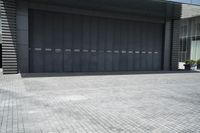 grey painted steel garage doors and brick floor on a concrete building with a concrete fence