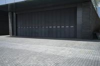 grey painted steel garage doors and brick floor on a concrete building with a concrete fence