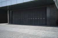 grey painted steel garage doors and brick floor on a concrete building with a concrete fence