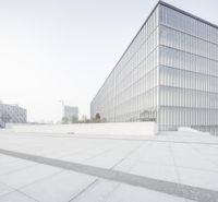 a large white building with lots of windows and a small gray wall around it while the image shows another building in the background