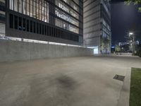 a concrete wall sits in an empty parking lot at night, illuminated by street lights