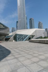 large building with a concrete courtyard next to it and several skyscrapers in the background