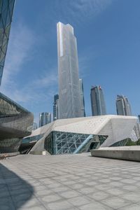 large building with a concrete courtyard next to it and several skyscrapers in the background