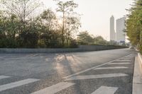 the road is empty and has arrows painted in white on it the trees are along the road