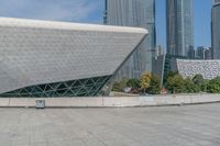 a young man skateboarding across an open area near the city buildings in the background