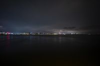 the city lights are shining brightly along the bay in the night sky over water and a large body of water