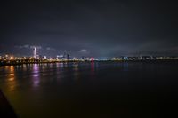 the city lights are shining brightly along the bay in the night sky over water and a large body of water