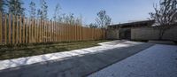 the wooden fence is built behind a walkway in the yard of a contemporary house in china