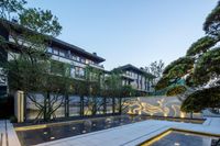 a large courtyard surrounded by trees in front of an apartment building at sunset time with outdoor lighting