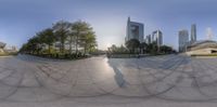 a view of a circular mirror in a park with tall buildings in the background with people standing outside and walking