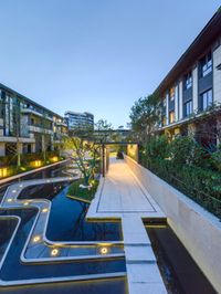 a building with large courtyard area at night next to a pool and trees around it