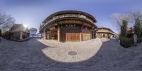 a circular lens photograph of a small building on a hill side street of china with its arched doorways