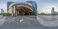 a fish eye lens picture of an entrance to a building with flags and the city skyline in the background