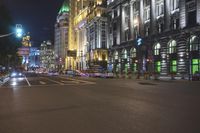 a city street at night showing a green traffic light and buildings with white lights and windows