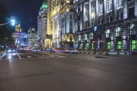 a city street at night showing a green traffic light and buildings with white lights and windows