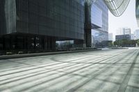 people walking in the shadows outside some tall buildings, and some buildings with glass windows and doors