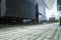people walking in the shadows outside some tall buildings, and some buildings with glass windows and doors