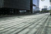 people walking in the shadows outside some tall buildings, and some buildings with glass windows and doors