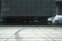 an empty concrete court with high rise buildings in the background, with shadows on the floor