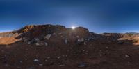 the sun shines behind the top of a mountain with rocks and other debris on it