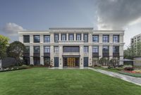 a building with two courtyards and a grassy yard in front of it on a beautiful day