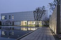 a building sitting in a field next to a reflecting pool in front of it,