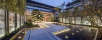 there are water features in the courtyard of an building at night time, lit by recess lighting