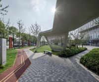 this building has a curved walkway and lots of green grass in front of it while the sun shines brightly on a clear blue sky