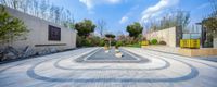 a circular patio with some stones in it and a sky with clouds behind it with the sun shining