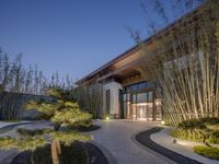 a house with bamboo trees in its courtyard and walkways by the house's entrance