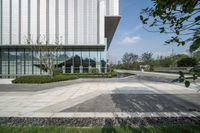 there is a square paved walkway in front of the building and trees surrounding it are next to two buildings