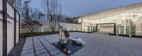 a statue of a woman stands in front of the glass building where a sculpture stands