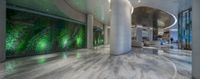 large glass walled lobby next to a stone column filled with furniture and art work of art